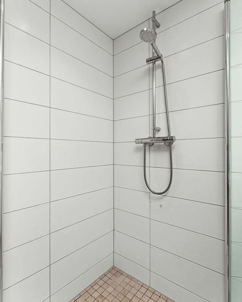 Bodengleiche Dusche ohne Stufe mit Glaswand und weißen Fliesen