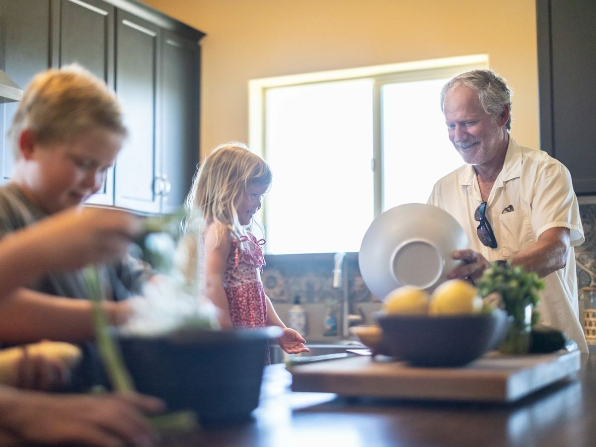 Großvater kocht mit seinen Enkeln in der sonnigen Küche seines Hauses